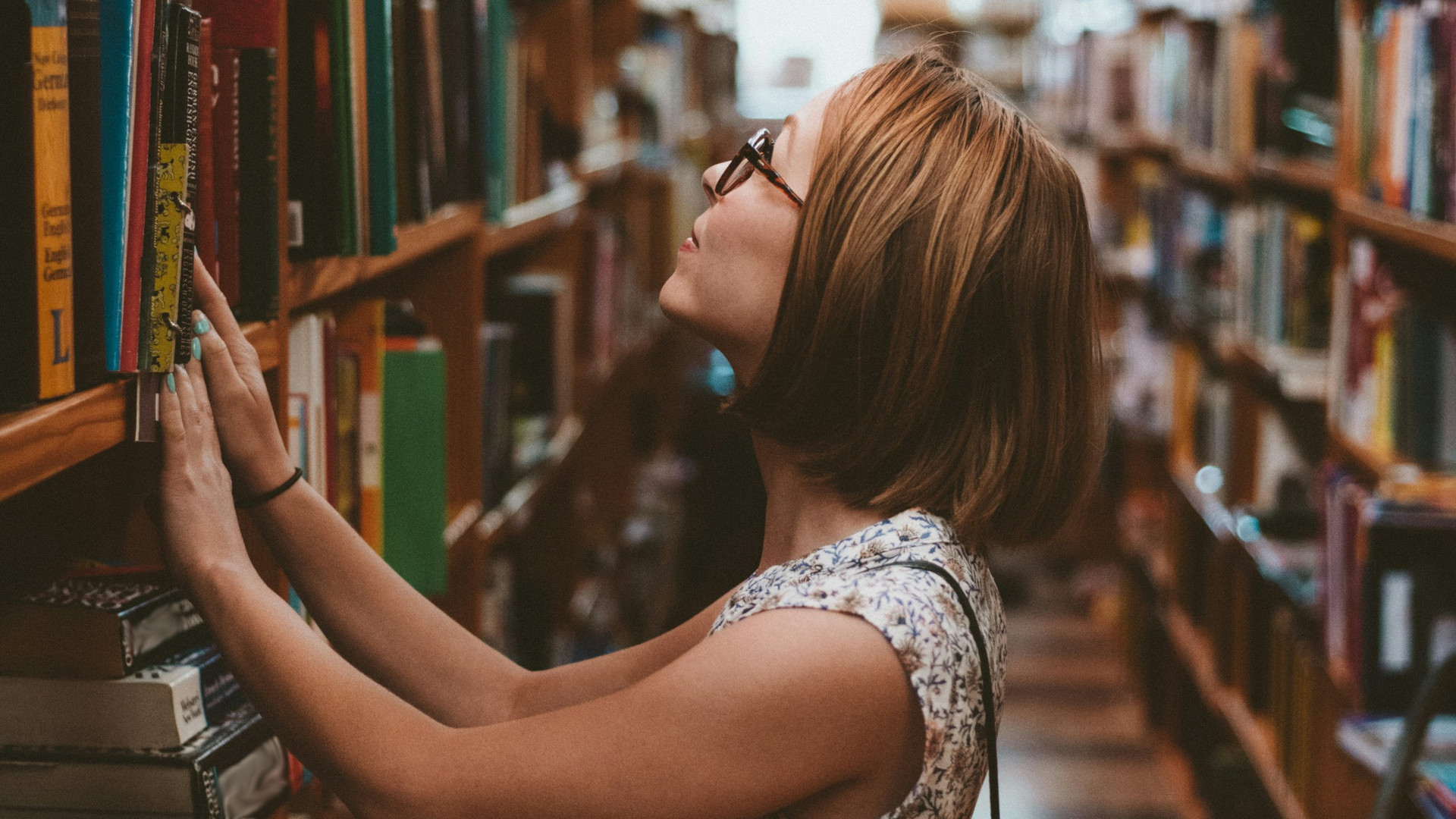 An overseas adult learner of English in a library of English language books.